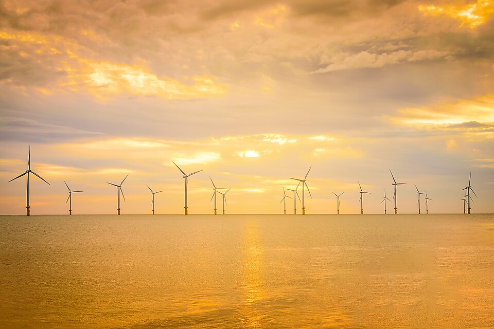 Wind turbines off shore in the sunset